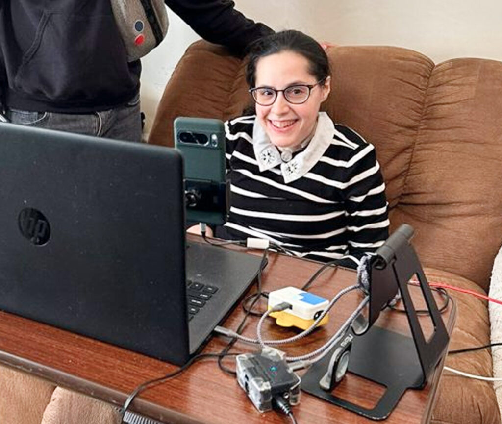 Esther smiling at the camera, seated and facing her laptop